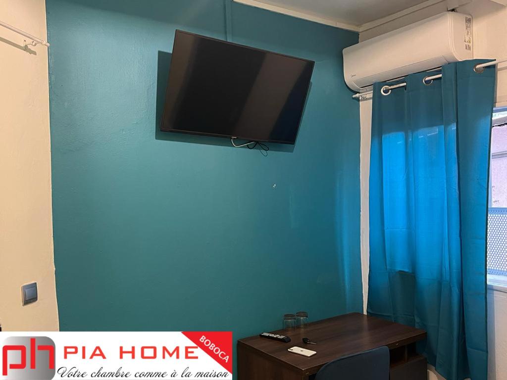 MamoudzouPIA HOME La Pompe的蓝色墙壁上配有平面电视的房间