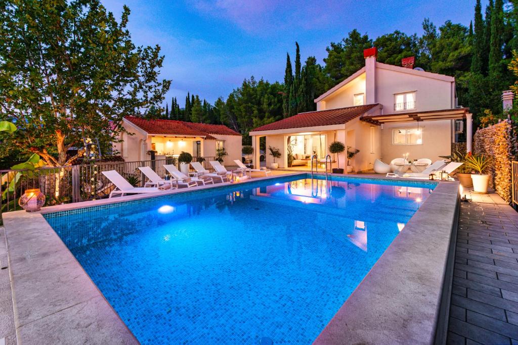 米利尼Luxury Vila Divina-Exceptional privacy的一个带椅子的游泳池以及一座房子