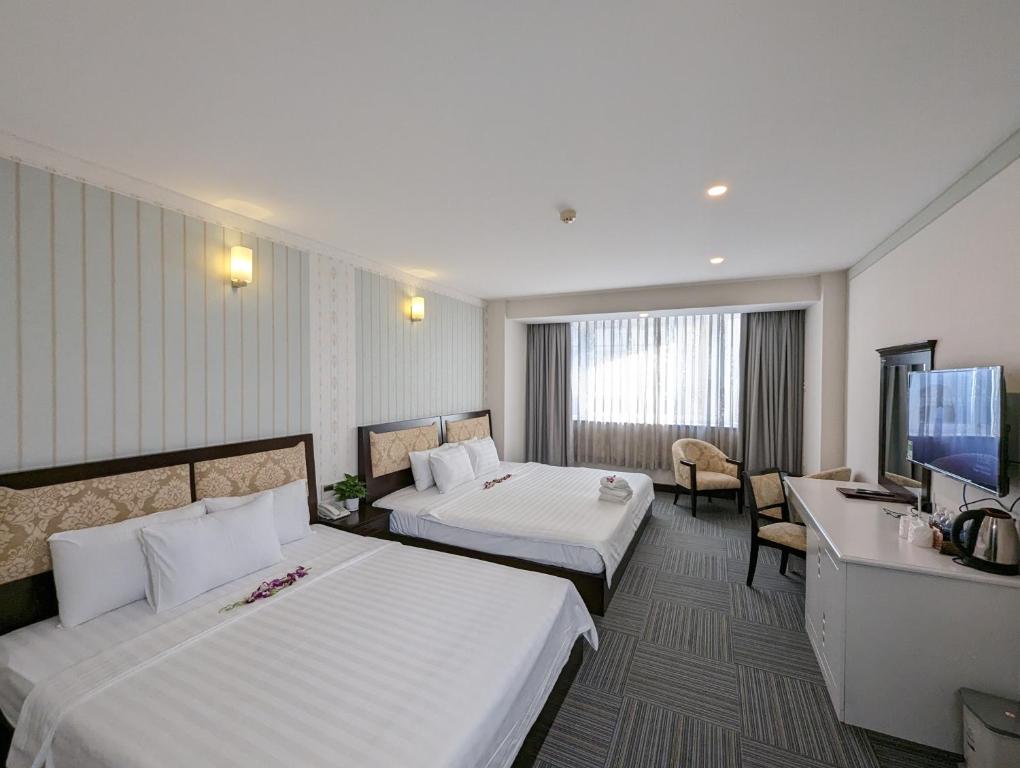 胡志明市Đông Kinh Hotel的酒店客房设有两张床和一台平面电视。