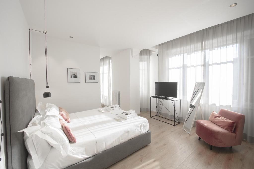 都灵San Carlo Suite Torino的白色卧室配有床和椅子