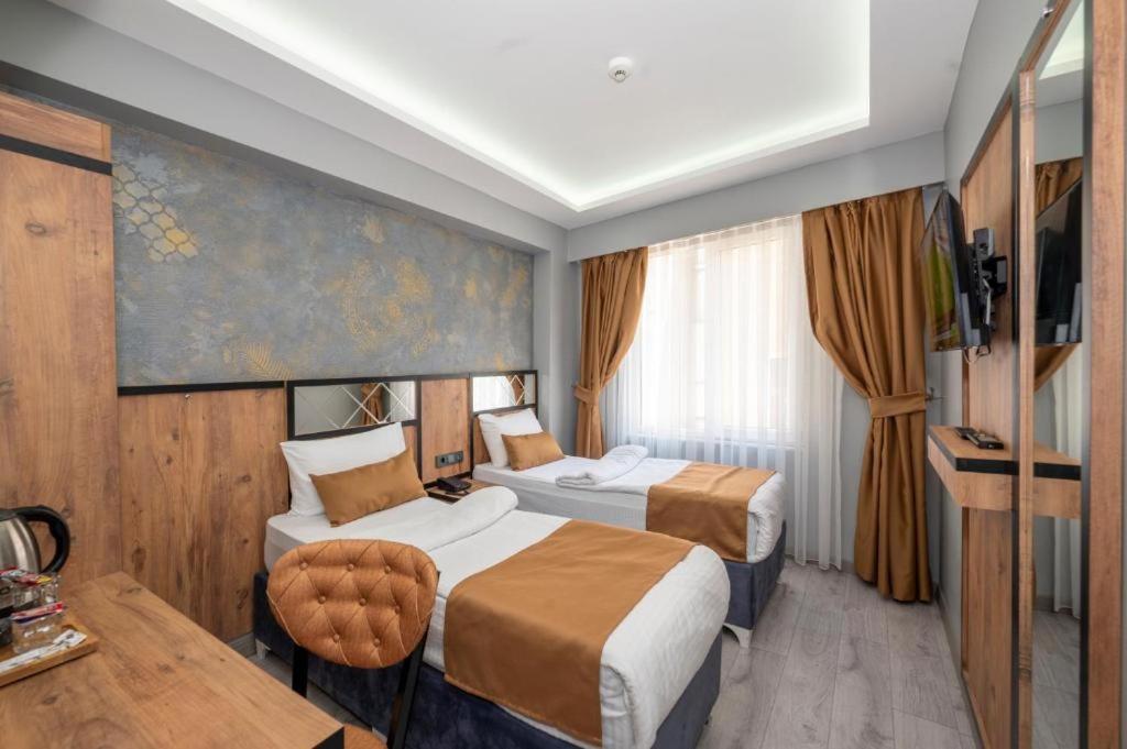 伊斯坦布尔Vizyon Hotel的酒店客房设有两张床和一张桌子。