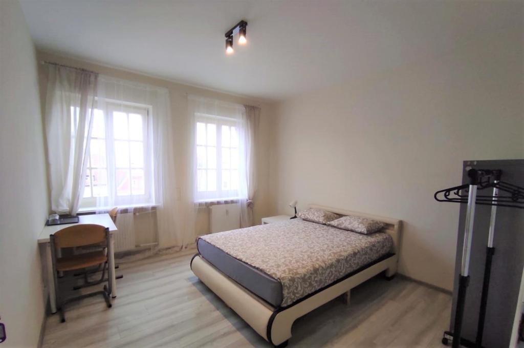 波兹南Rynek 9的一间卧室配有一张床、一张书桌和两个窗户。