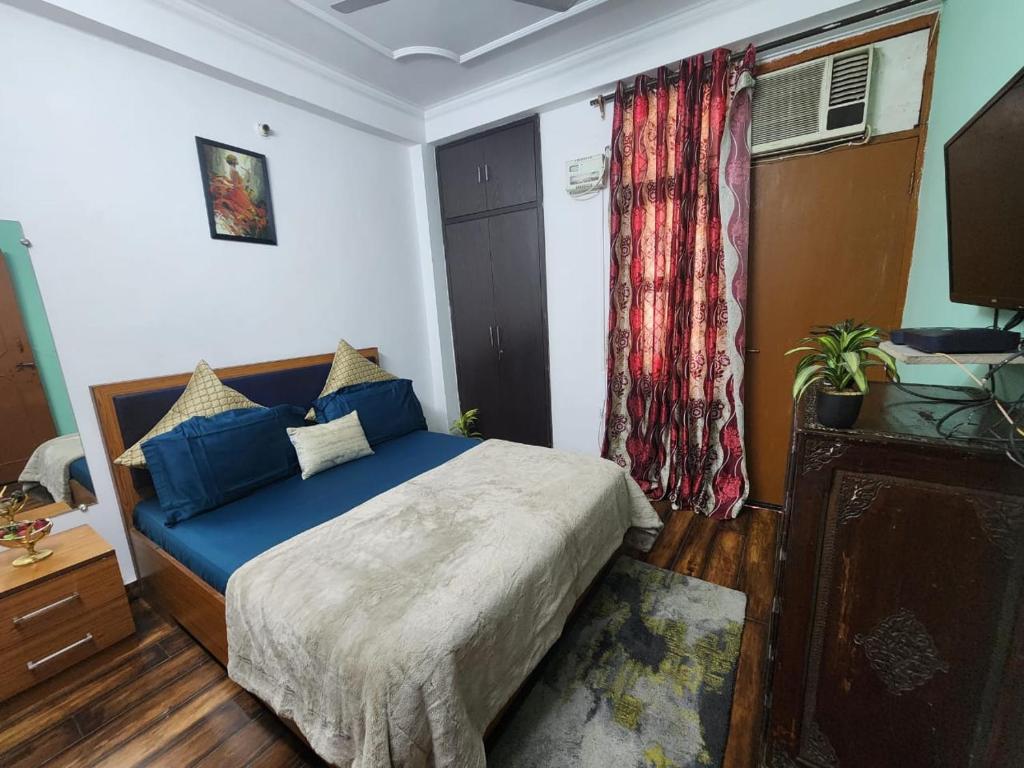 新德里Homlee-Best Value flat with kitchen Near Metro的一间卧室配有一张带蓝色床单的床和一扇窗户。