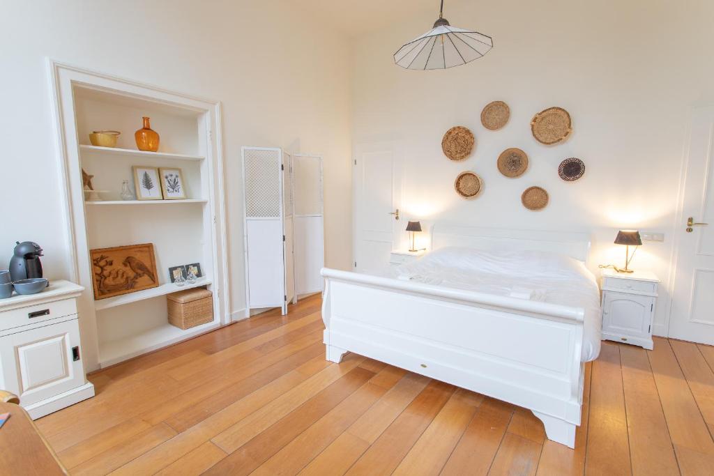 聚特芬De Dekenije的卧室配有白色的床,铺有木地板