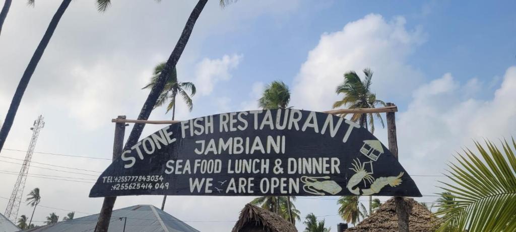 江比阿Stonefish Inn Jambiani的棕榈树海滩上餐厅标志