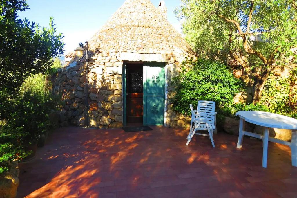 多尔加利Casa in campagna的一座小石头建筑,在庭院里配有桌椅