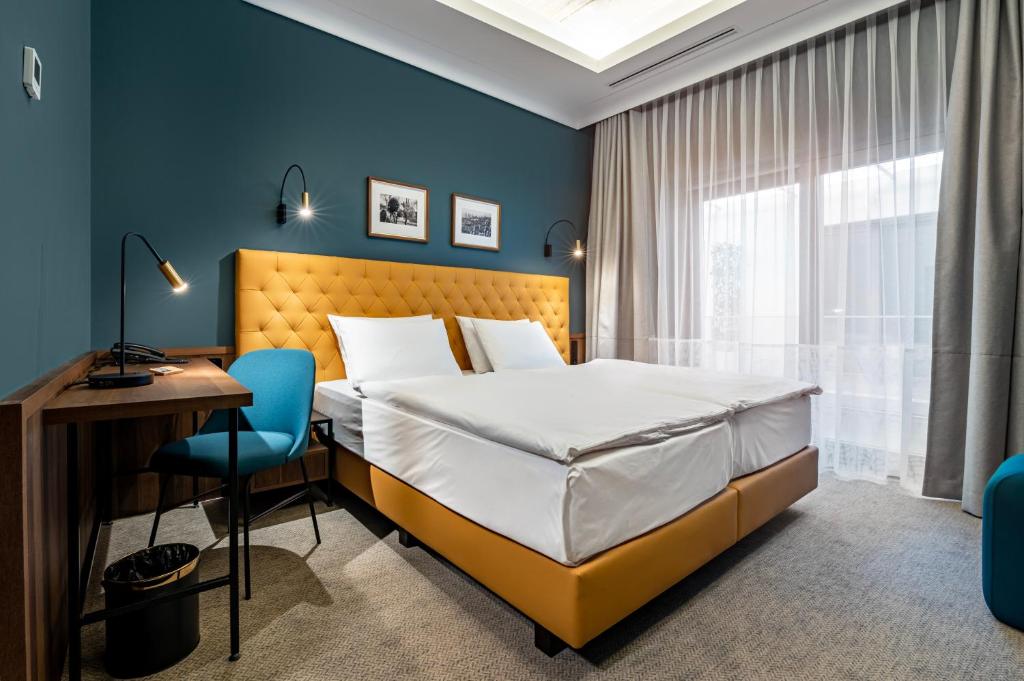 佩奇Palatinus Boutique Hotel的一间卧室配有一张床、一张书桌和一个窗户。
