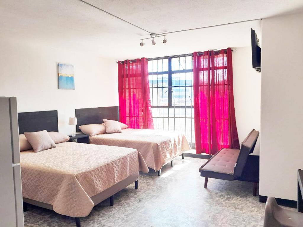 危地马拉Hospedaje Via 7的客房设有两张床和一个带粉红色窗帘的窗户。
