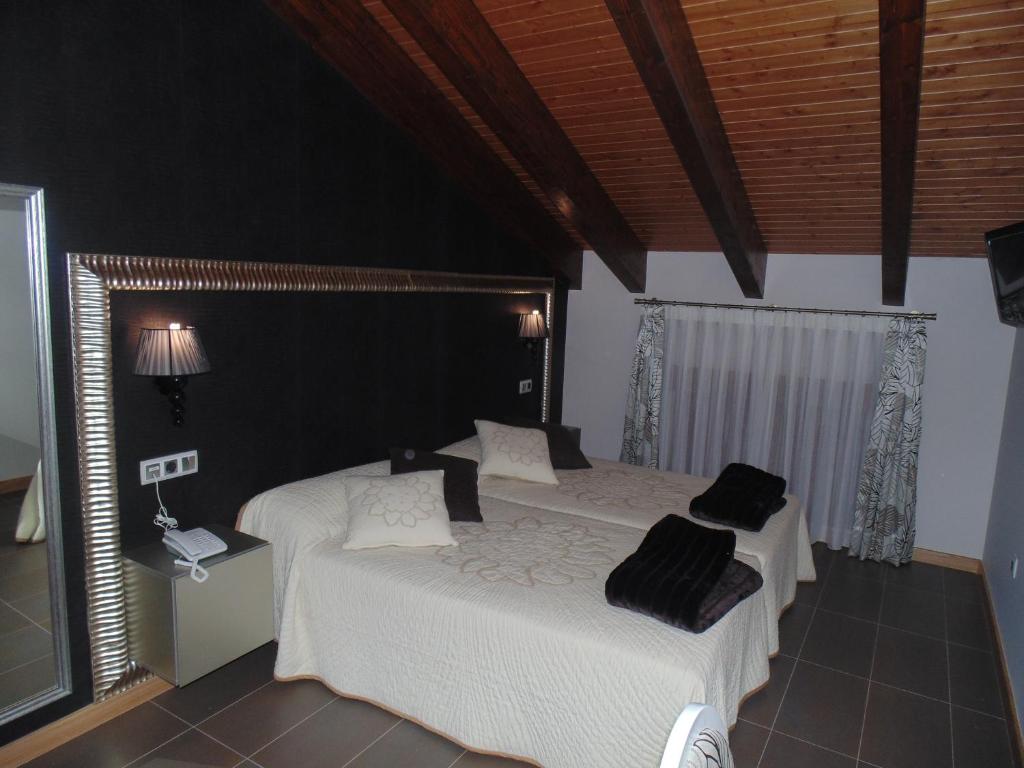Langa de Duero里贝拉德兰加酒店的一间卧室配有两张床,提供白色的床单和黑色的枕头