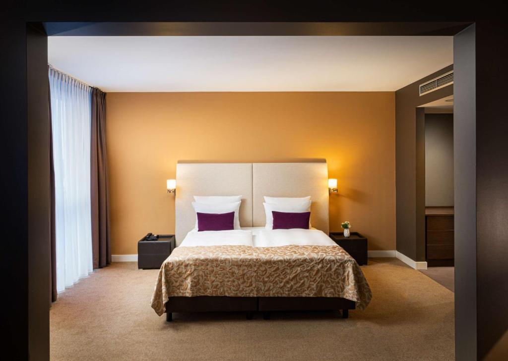 慕尼黑慕尼黑瑞拉诺酒店的一间卧室配有一张带紫色枕头的大床