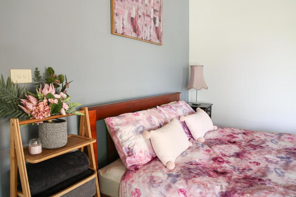 CorryongJardine Lodge - Can sleep 22!的一间卧室配有一张粉红色花卉图案的床铺