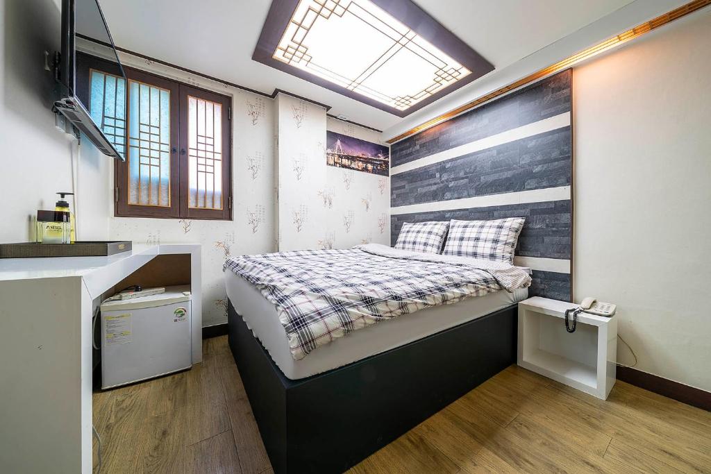 首尔明洞京东酒店的一间小卧室,配有一张带木制床头板的床