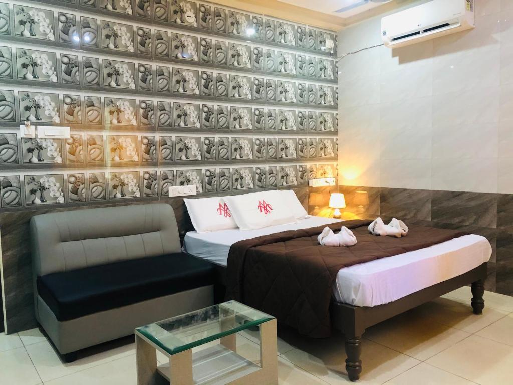 钦奈MARINA PALACE的一间卧室设有两张床和一张沙发,墙上设有板子