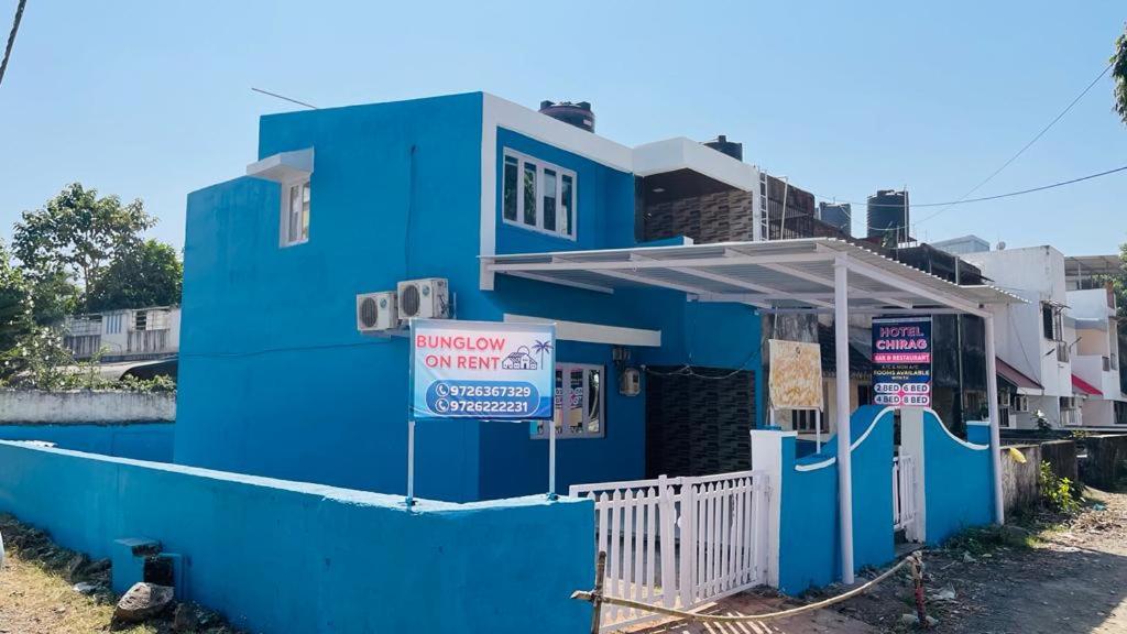 达曼Chirag Banglow 2BHK的蓝色的建筑,前面有标志