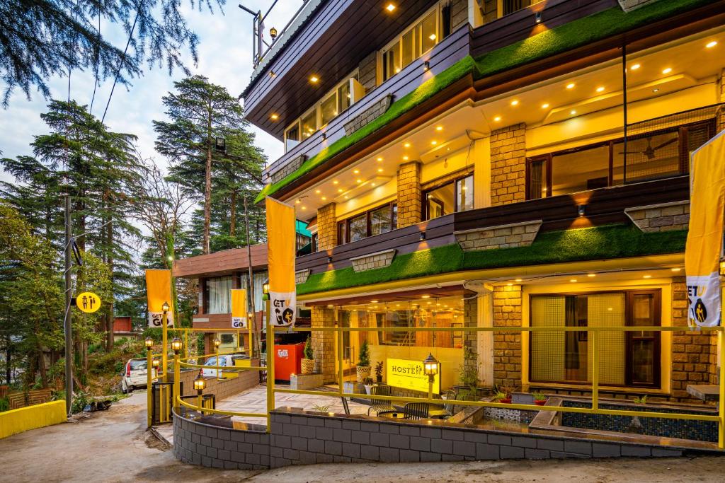 麦罗肯机The Hosteller Mcleodganj, Mall Road的一座高大的建筑,旁边灯火通明