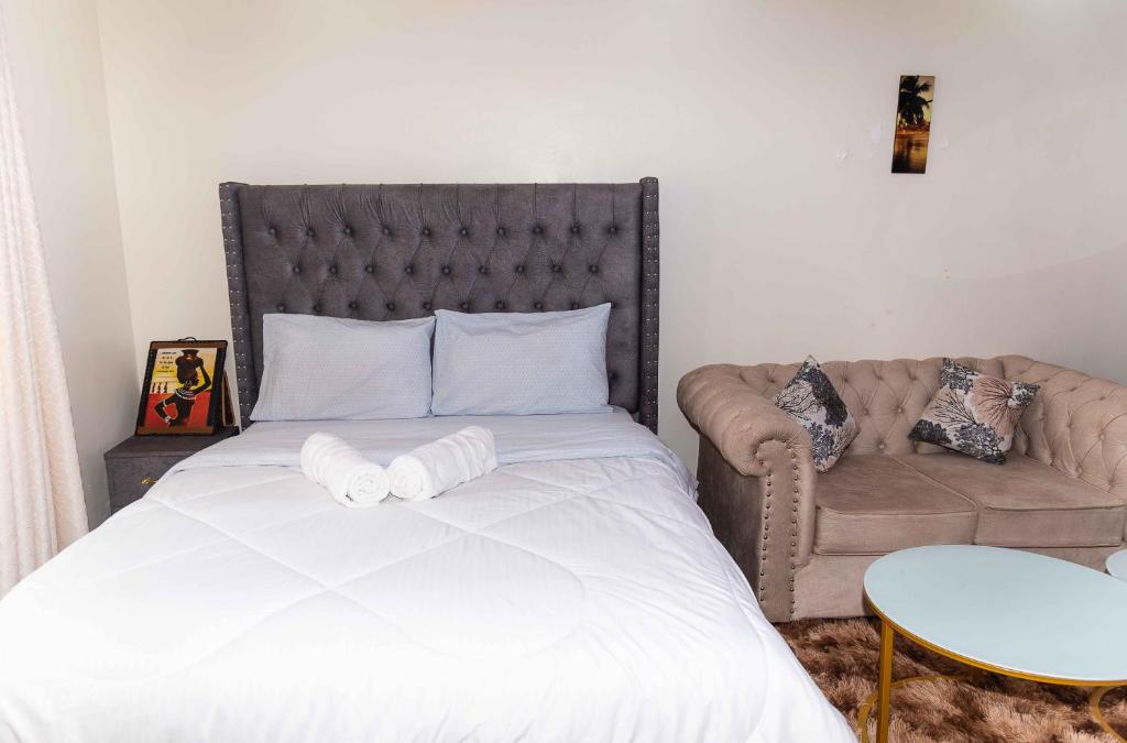Langata RongaiSpringStone Studio Apartment Rm 19的一间卧室配有一张大床和一张沙发