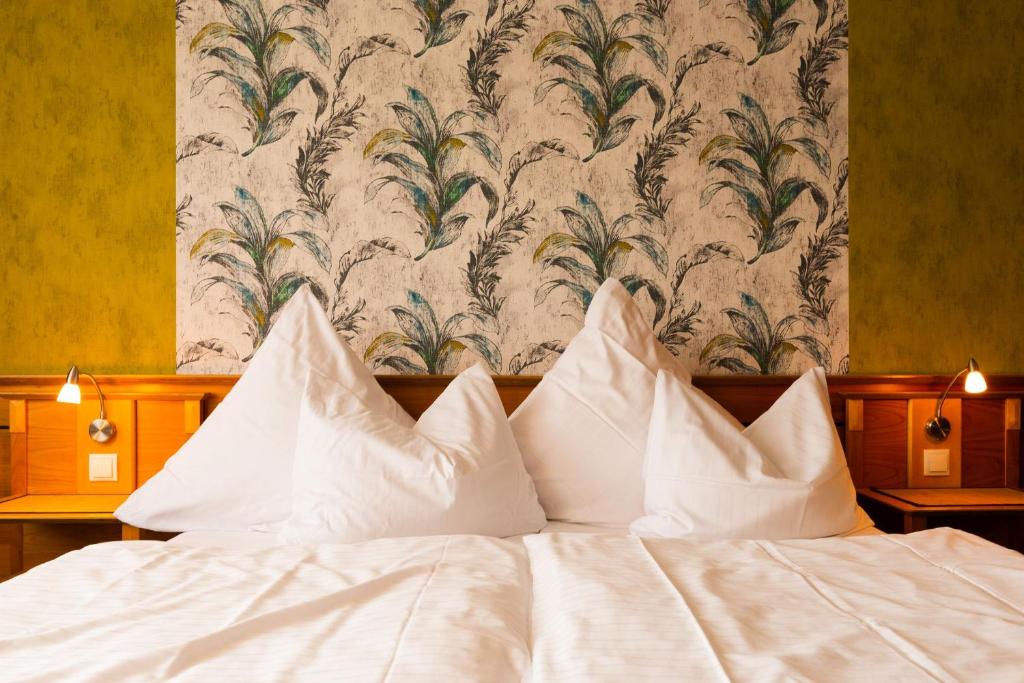 伊普霍芬Biobausewein WEIN HOTEL LEBEN的壁纸前的一张带白色枕头的床