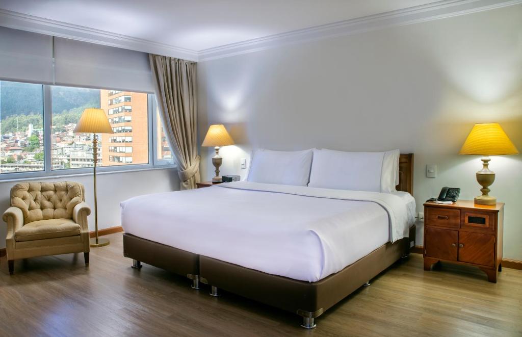 波哥大GHL Hotel Tequendama Bogotá的卧室配有床、椅子和窗户。