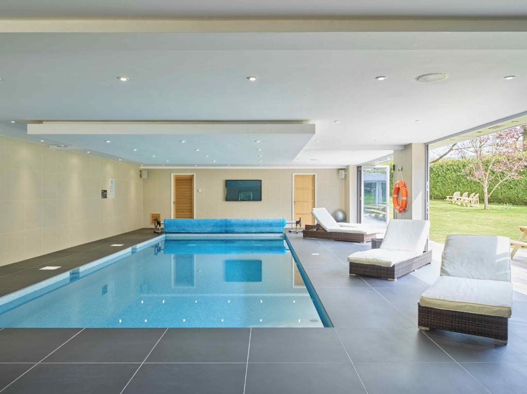 Charlton KingsCheltenham's Most Luxurious House的一个带椅子和沙发的房子内的游泳池