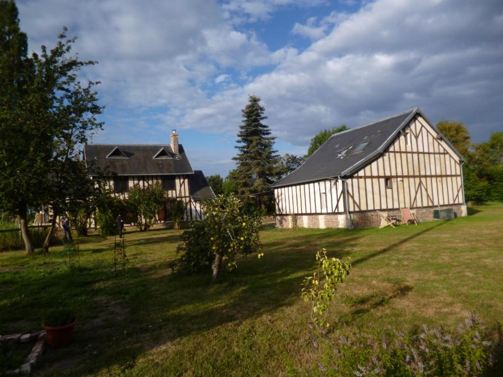 Neuville-sur-TouquesLA VILLA QUI A DU CHIEN的田野中的一个大谷仓和房子