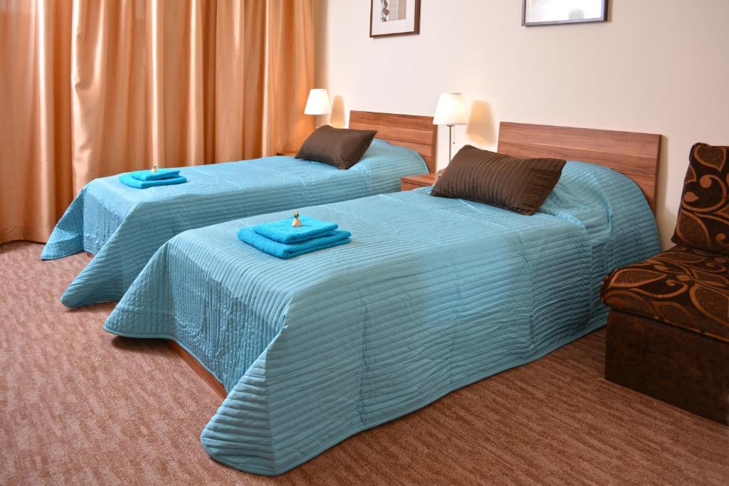 韦切什机场格罗塞尔酒店的一间设有两张带蓝色床单和椅子的床的客房