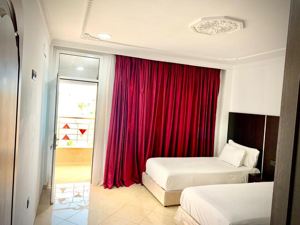 纳祖尔HOTEL BEAUTIFUL的酒店客房设有两张床和红色窗帘