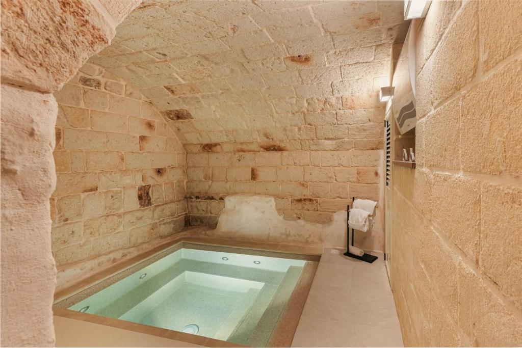 法萨诺[Exclusive - Suite] SPA con Idromassaggio Jacuzzi的带浴缸的石墙浴室