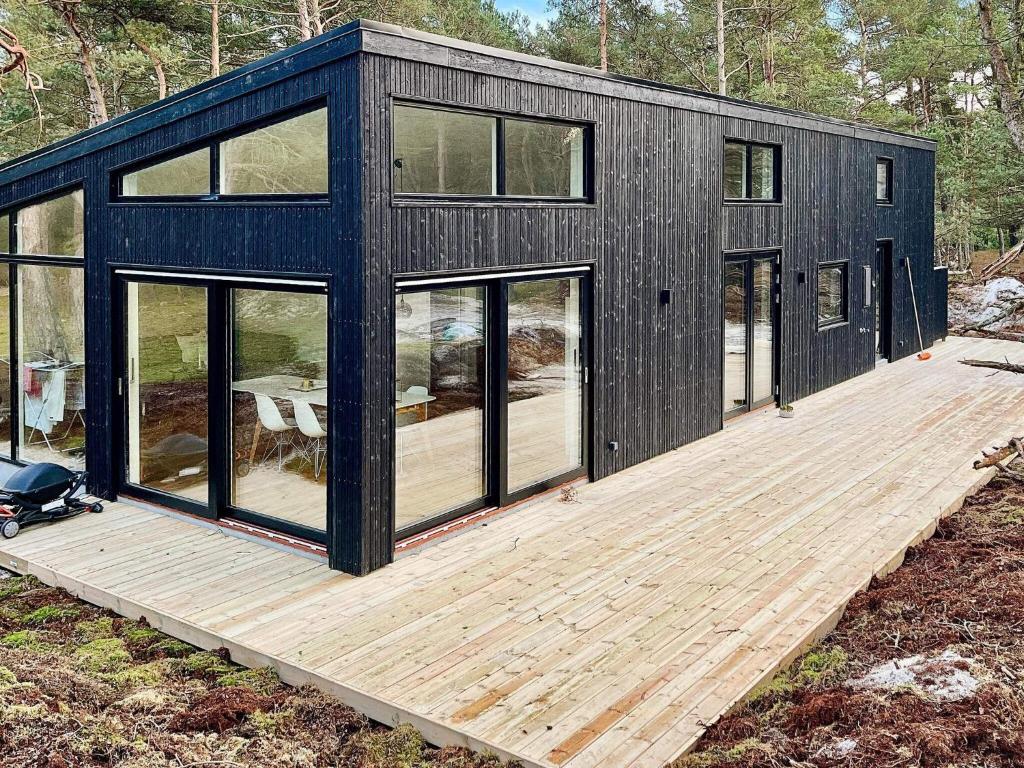 维斯特索马肯Holiday home Nexø XLI的黑色的模块化房屋,设有木甲板