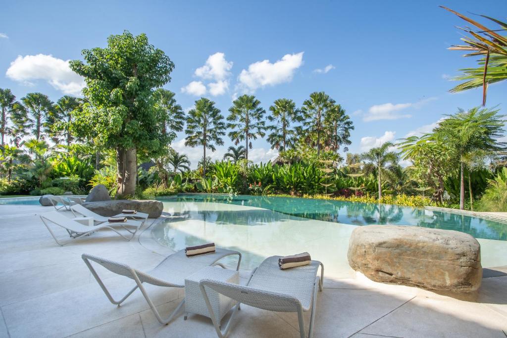 苏卡瓦提Sanctoo Suites & Villas的一个带椅子和大岩石的度假游泳池