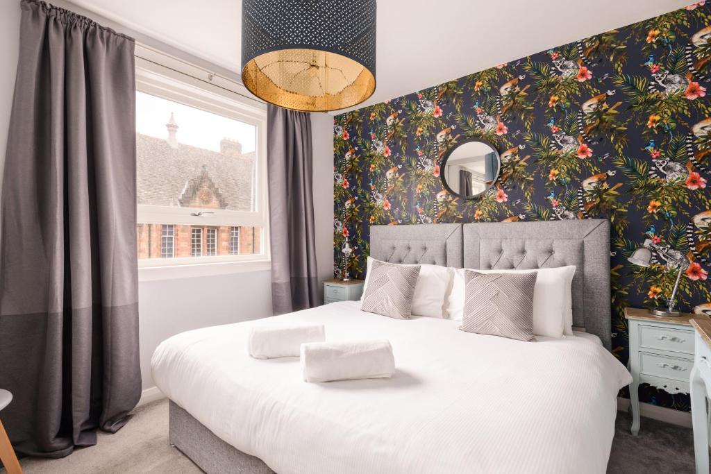 爱丁堡The Canongate Apartment的一间卧室配有一张带花卉壁纸的大床