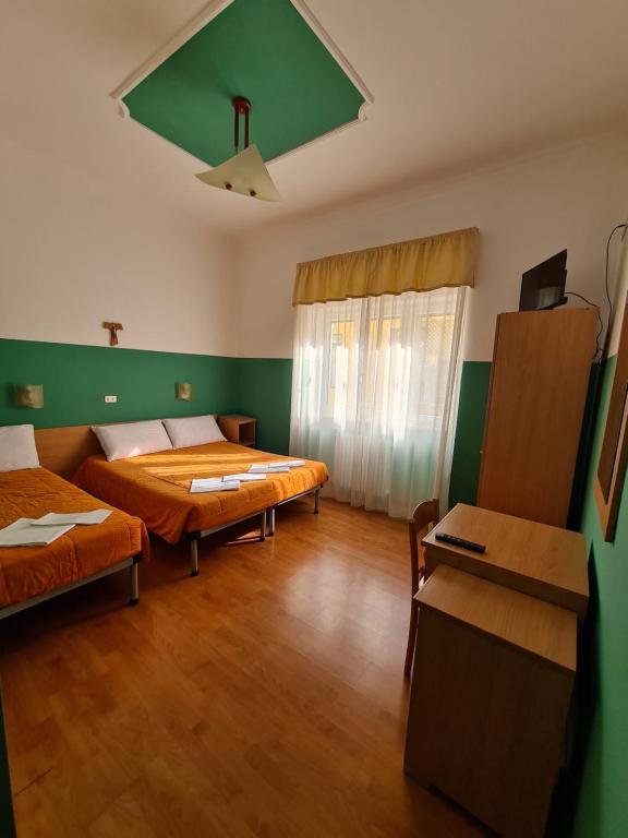 圣乔瓦尼·罗通多B&B Santa Lucia的配有绿色墙壁和木地板的客房内的两张床