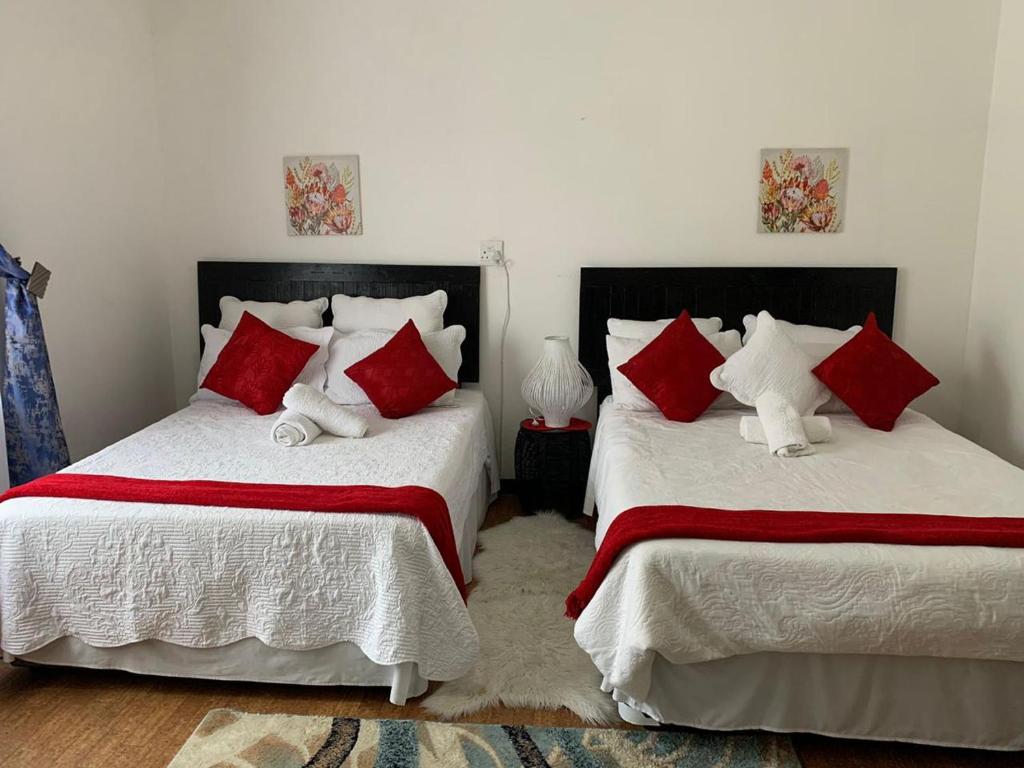 马盖特TSGuesthouse的一间卧室配有两张带红白色枕头的床
