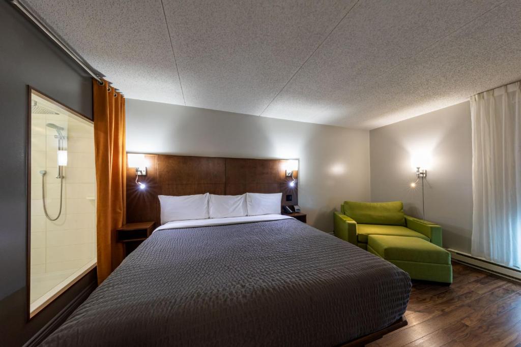 魁北克市Hôtel & Suites Normandin Québec的一间卧室配有一张床和一把绿色椅子