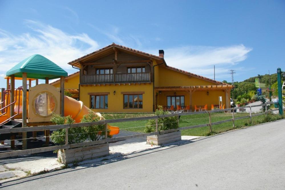 Camping El Roble Verde的黄色的房子,前面有一个游乐场