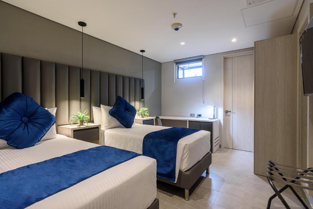 麦德林4 Sur Hotel的酒店客房 - 带两张带蓝色枕头的床