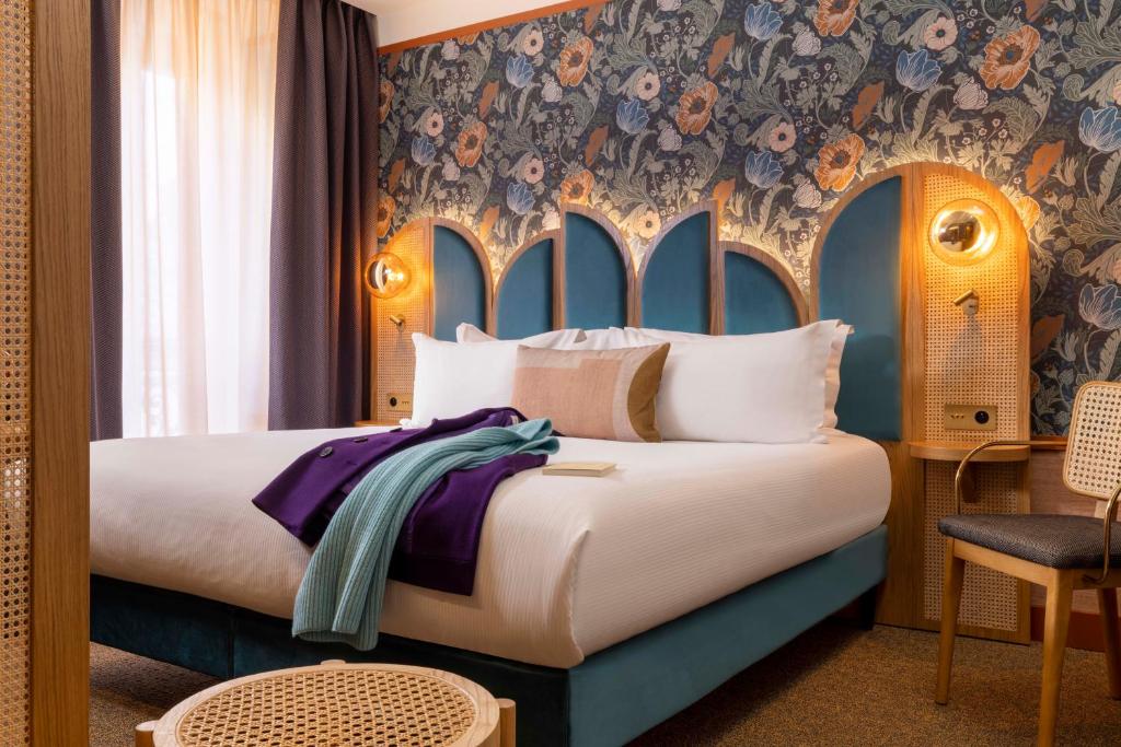 巴黎Hôtel Jardin de Cluny的一间卧室配有一张带花卉壁纸的大床