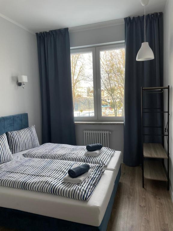 埃尔布隆格Aparthotel Dworzec的一间卧室配有一张带蓝色窗帘的床和一扇窗户