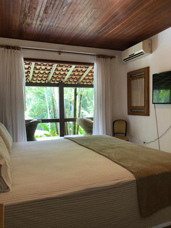 安格拉杜斯雷斯Sítio Bagatelle com cachoeira e piscina!的一间卧室设有一张大床和一个窗户。