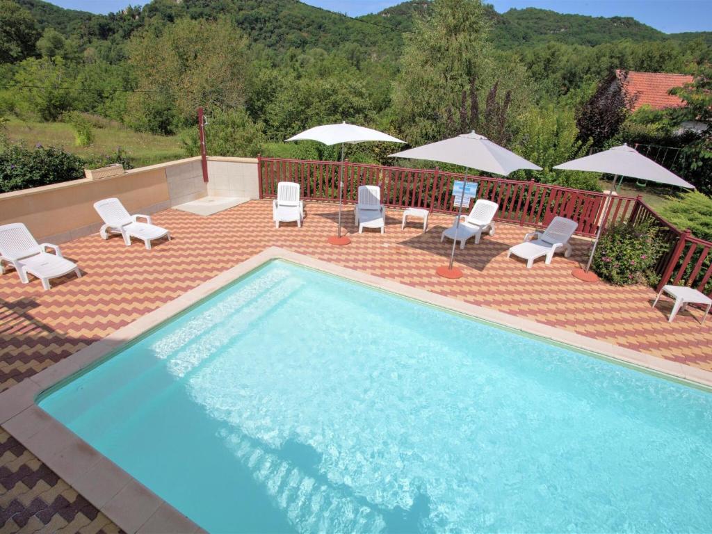 CarluxHoliday home with private pool near Sarlat的庭院内一个带椅子和遮阳伞的游泳池