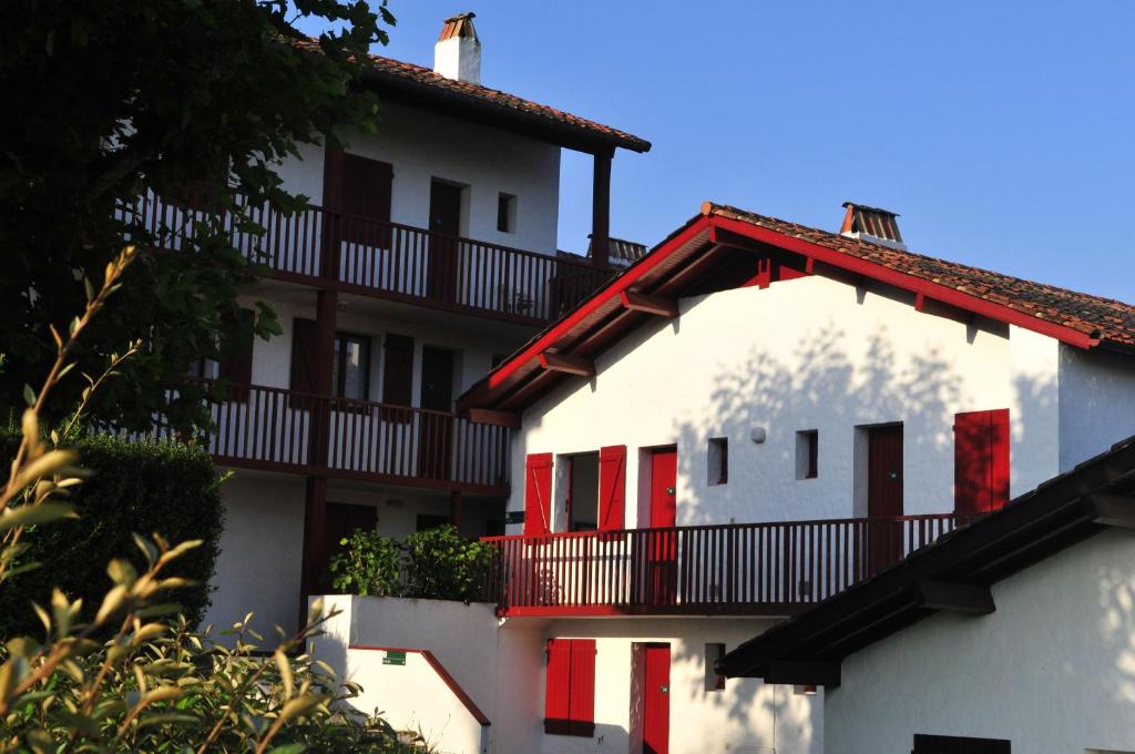萨尔VVF Pays Basque Sare La Rhune的白色的建筑,设有红色的窗户和阳台