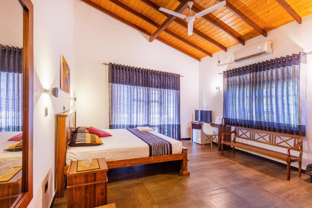 MalabeYamu Lanka Inn的卧室配有一张床、一张书桌和窗户。