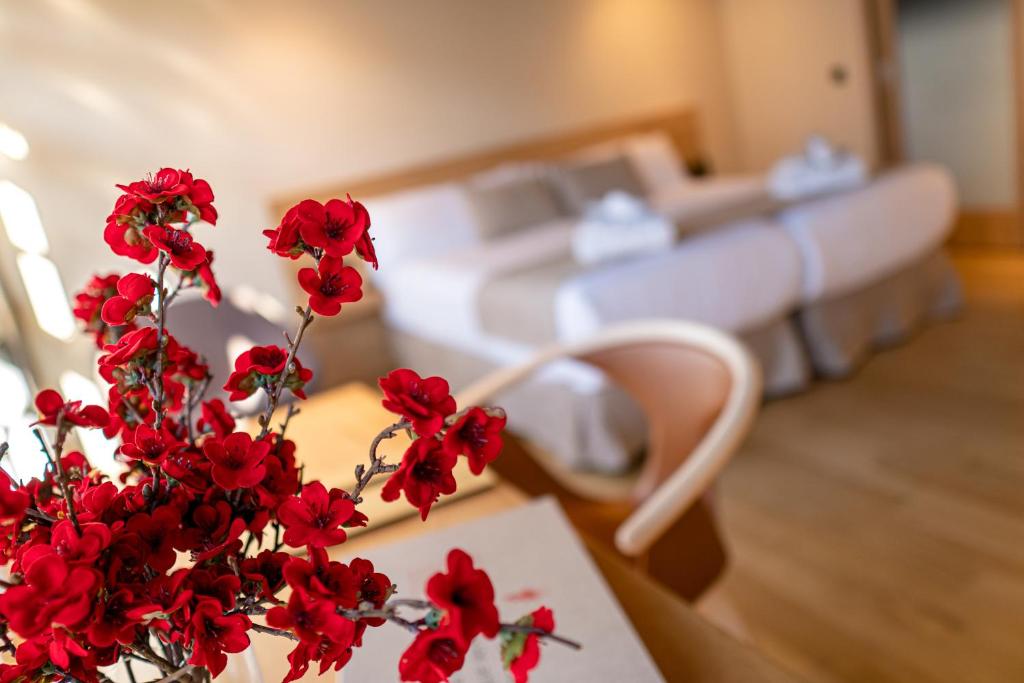 塞拉诺瓦ACOUGA Hotel Boutique的卧室里的一个带红色鲜花的花瓶