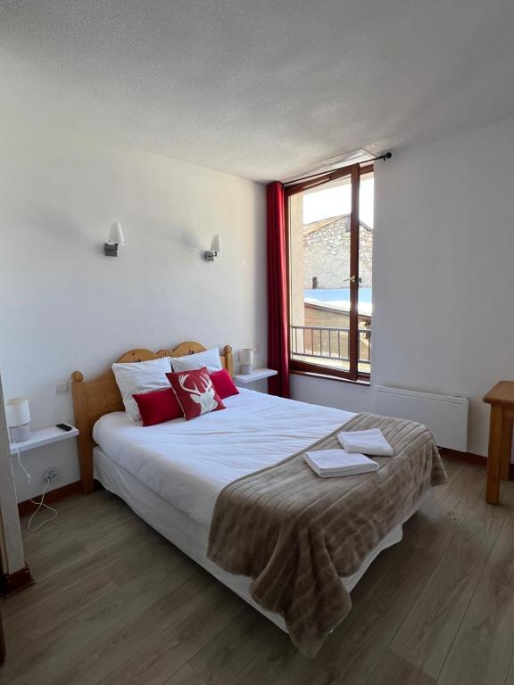 阿尤克斯Auberge La Cascade的一间卧室配有一张带红色枕头的大床和窗户