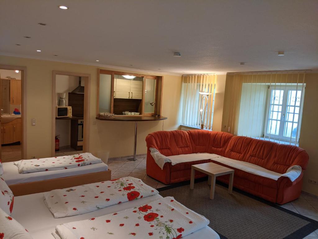 楚斯马尔斯豪森阿德勒客栈酒店的客厅配有两张床和一张红色沙发