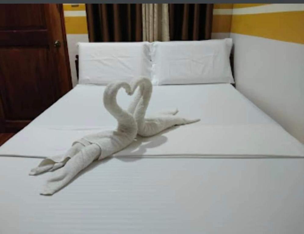 科隆SUN'S TRAVEL AND TOURS AGENCY CORON PALAWAN的床上的两只天鹅雕塑