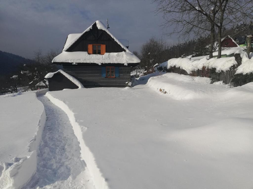 奥什恰德尼察Chata Kolmanovci的雪覆盖着房子,有小径
