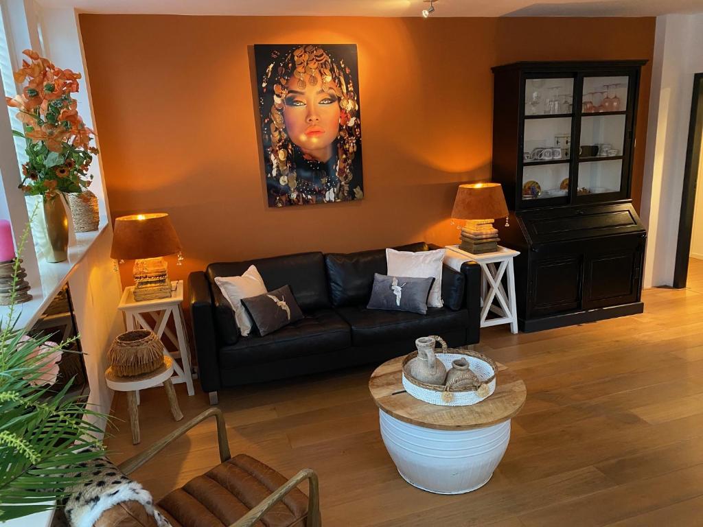 赞德沃特瓦可胡赛迪泽帕瑞度假屋的客厅配有黑色沙发和绘画作品