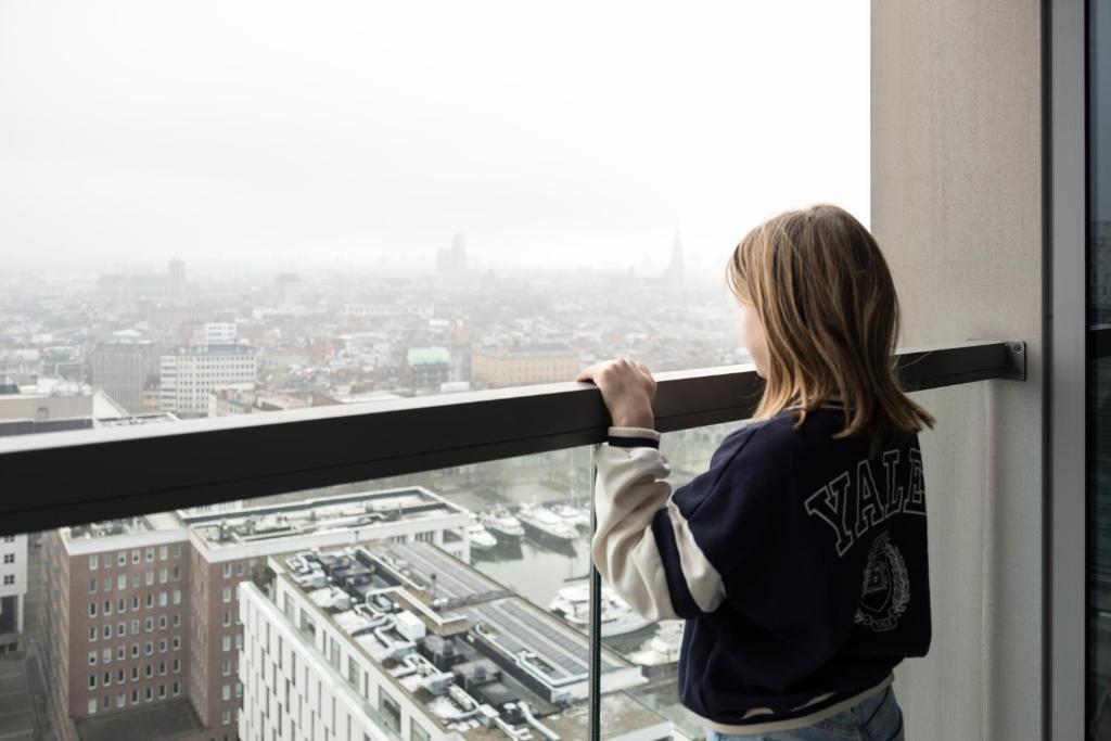安特卫普UNIEK appartement - mooiste en hoogste uitzicht op Antwerpen! - incl gratis parking的窗外城市的女人