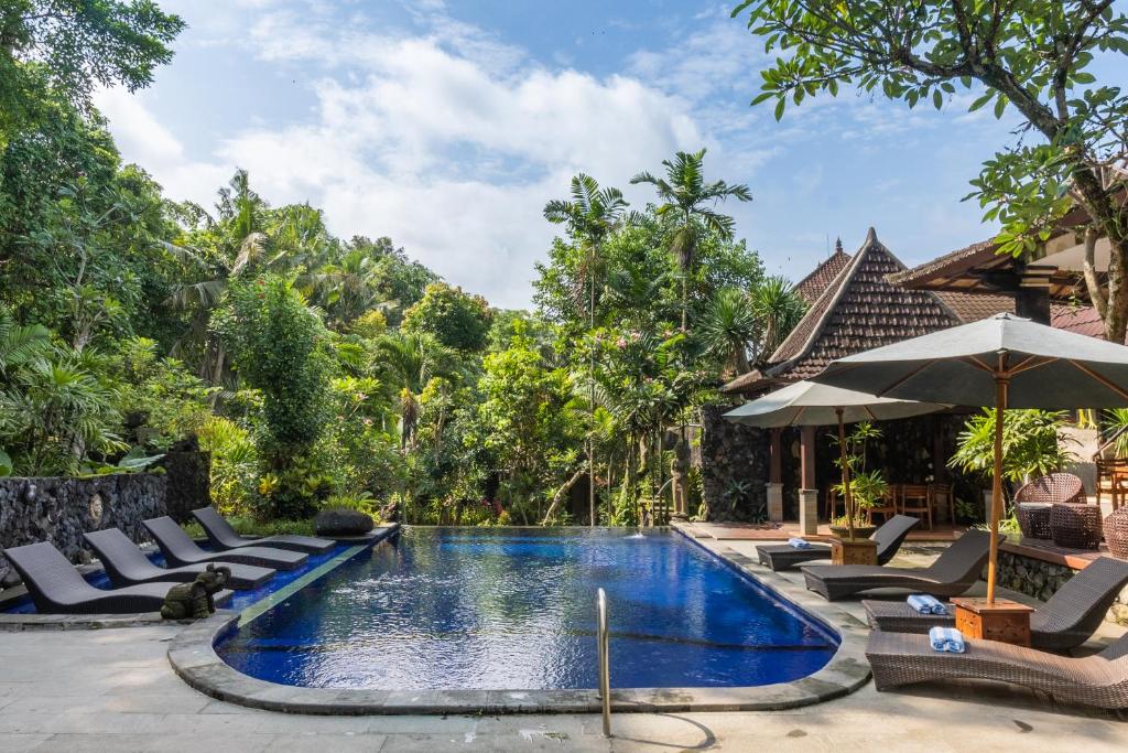 乌布Dewangga Ubud的一个带躺椅和遮阳伞的度假村游泳池