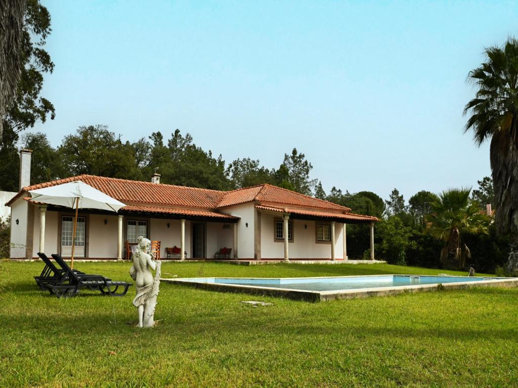圣塔伦Fantástica Casa de Campo com Piscina perto de Lisboa的庭院中带游泳池和雕像的房子